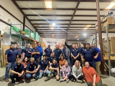 Southern Air Cooling, Heating, & Electrical team members gathered in warehouse with Happy Fall banner displayed.