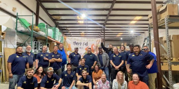 Southern Air Cooling, Heating, & Electrical team members gathered in warehouse with Happy Fall banner displayed.