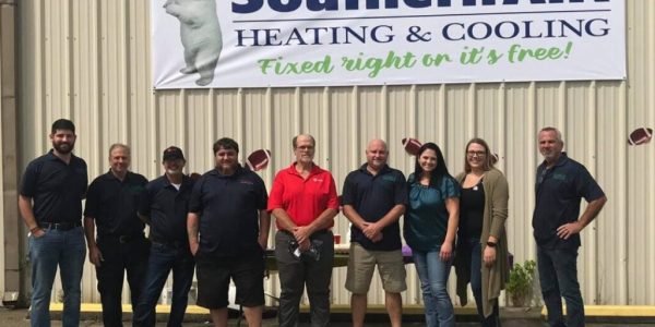 Team of Southern Air Heating & Cooling employees standing in front of company building with logo and tagline 'Fixed right or it's free!'