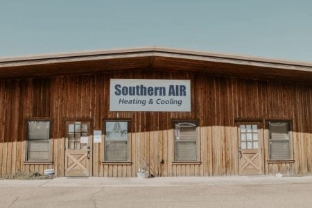 Wooden storefront building with Southern AIR Heating & Cooling sign and beige lower panels.